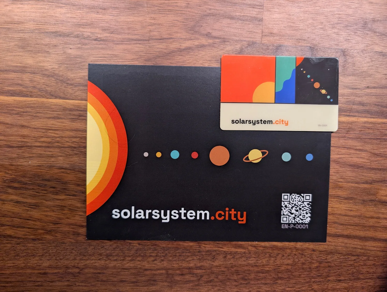 The Sun Card resting on the World Trade Center mission postcard, showing how much larger the postcard is.